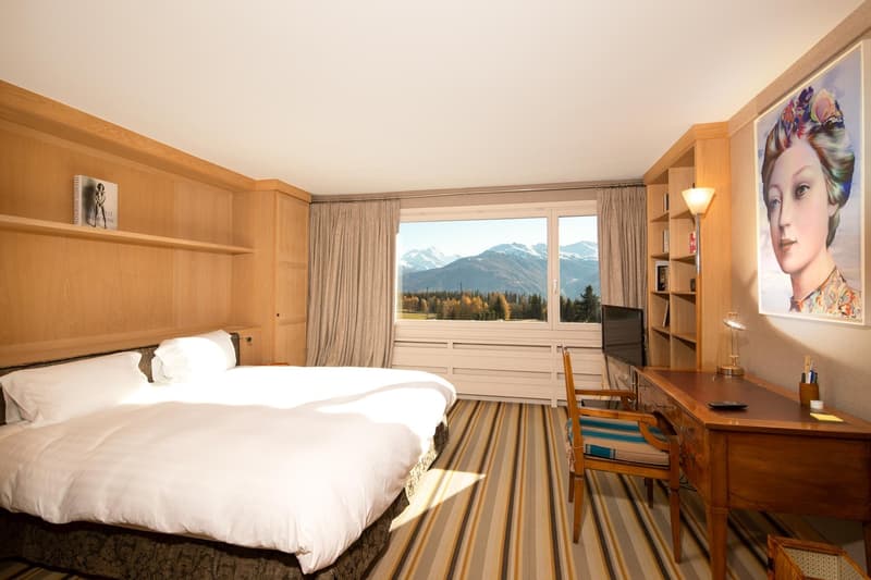 large bed, wooden desk, wooden chair, large window, wooden shelves, painting, television