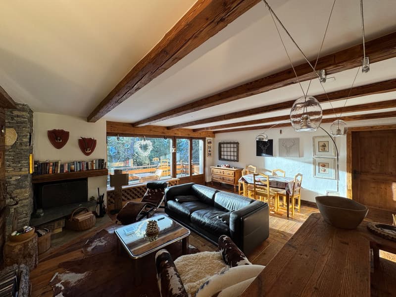 wooden beams, fireplace, large windows, wooden floor, black leather couch, coffee table, armchairs, dining table, wooden cabinet, picture frames, wooden door