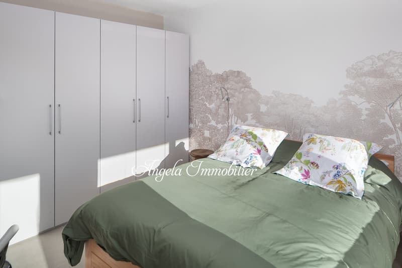 white wardrobe, green bed spread, floral pillows, desk, wall with tree print