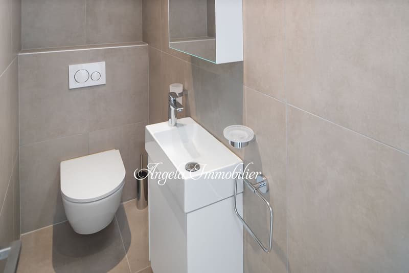 Modern bathroom, wall-mounted toilet, rectangular vanity with sink, wall-mounted mirror, light beige tiles