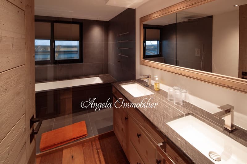 Spacious bathroom with dark tile walls, large mirror, vanity with sink, and a private washing machine