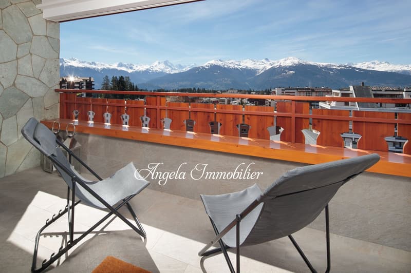 balcony with wooden railing, two folding chairs, mountain view