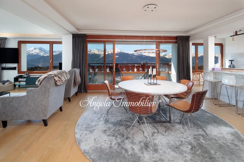 modern dining area with a round table, chairs, and a chandelier, large windows with a view of the mountains, a couch, and a television