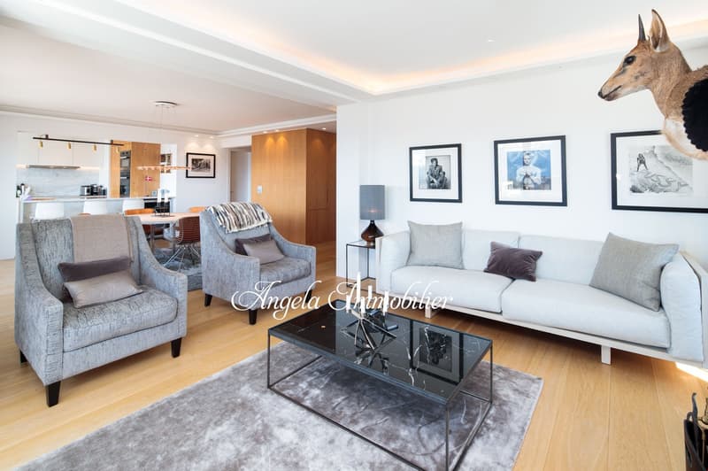 living room with wooden floors, glass coffee table, grey couches, armchairs, wall pictures, lamp, rug, animal head mounted on wall