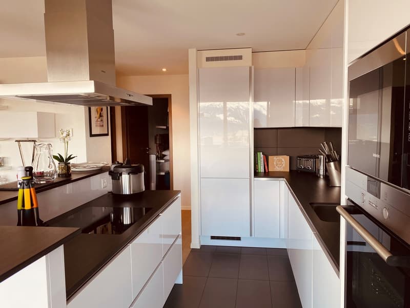 modern kitchen with white cabinets, black countertops, stainless steel appliances, and a large window