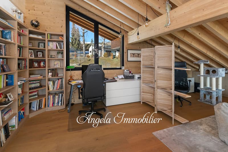 Spacious home office with wooden beamed ceiling, large windows overlooking a scenic outdoor view, built-in bookshelves, desk, office chair, and various decor items