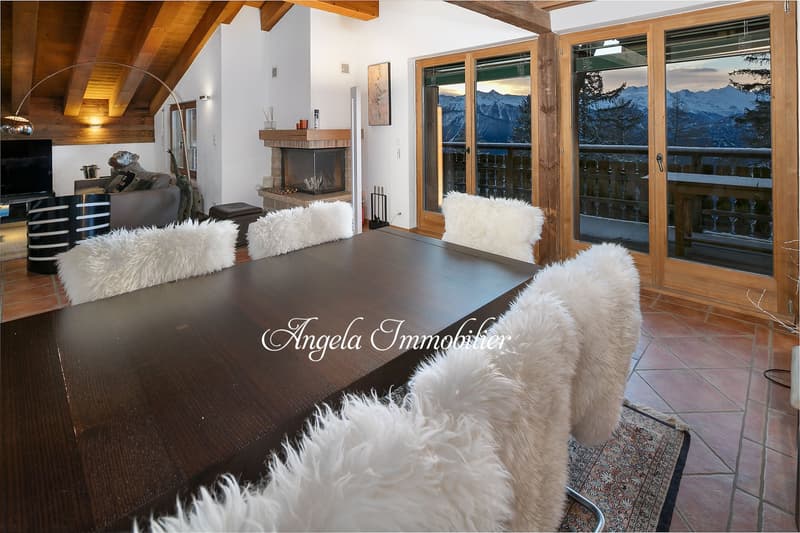 dining room with large table, white fur chairs, fireplace, large windows, balcony, mountains view