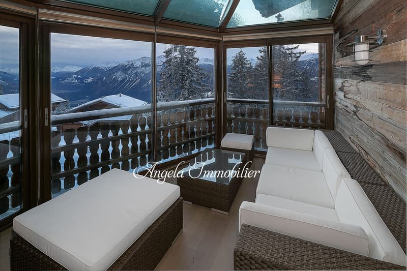 balcony, large windows, sofa, coffee table, wooden wall, mountain view
