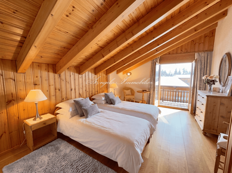 Two beds, wooden ceiling, wooden walls, wooden floor, balcony, window, lamp, rug, dresser, flowers