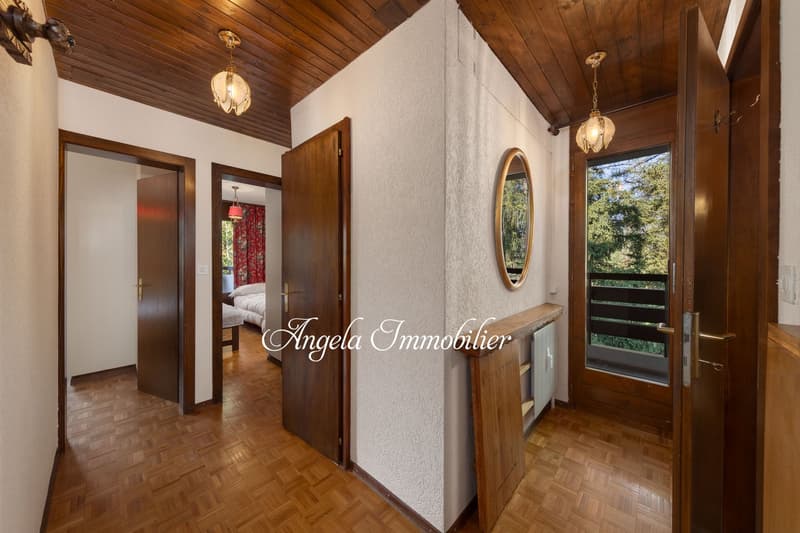 Wooden ceiling, white walls, wooden floor, three doors, mirror, lights, view outside.