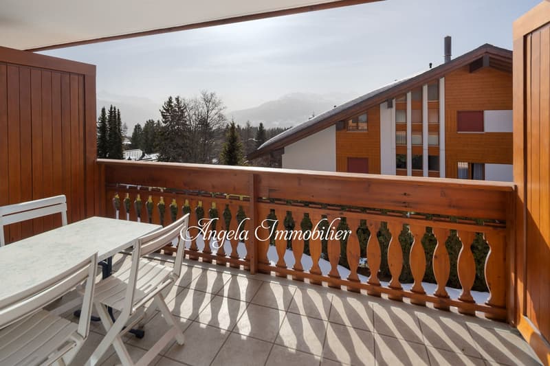 Balcony with wooden railing, table and chairs, tiled floor, view of mountains