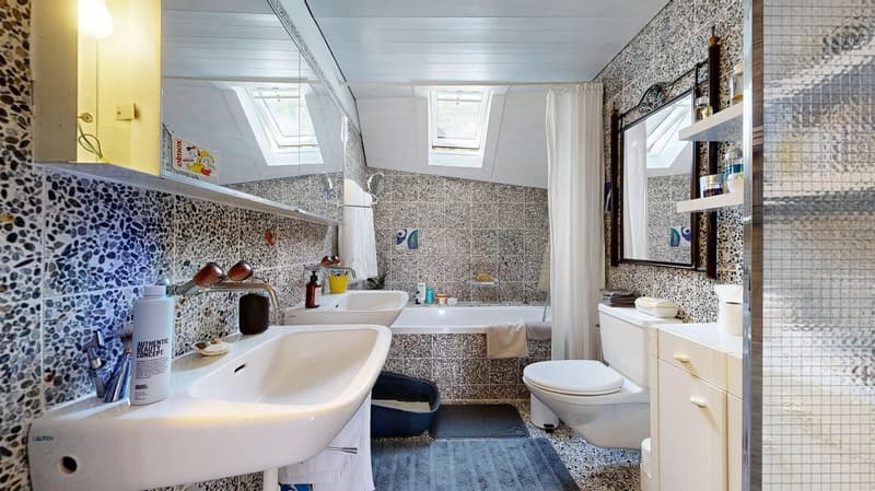 Two sinks, bathtub, toilet, floor to ceiling mirrors, tiled walls, skylights