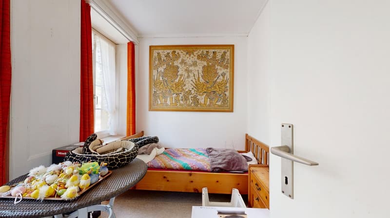 room with bed, painting on wall, table with basket, carpeted floor