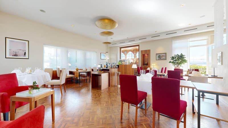 restaurant with tables and chairs, large windows, wooden floor, framed pictures on the wall