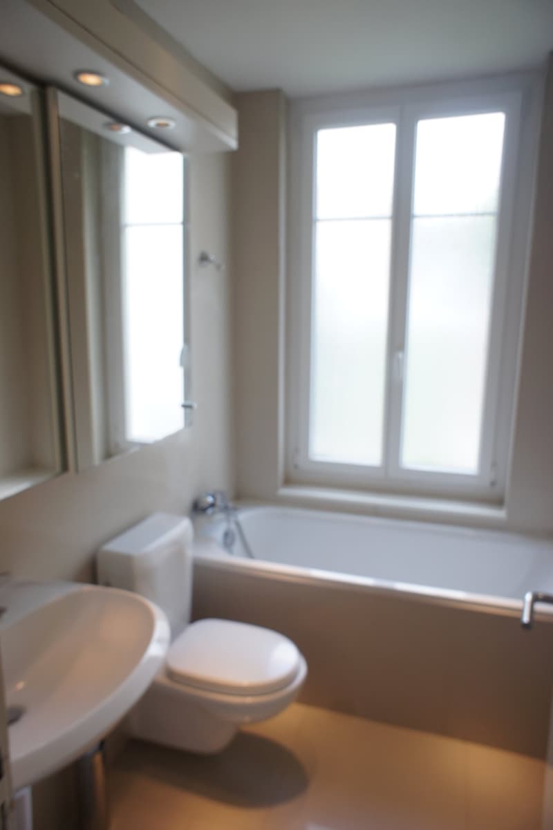 Bathroom with white bathtub, toilet, sink, and mirror