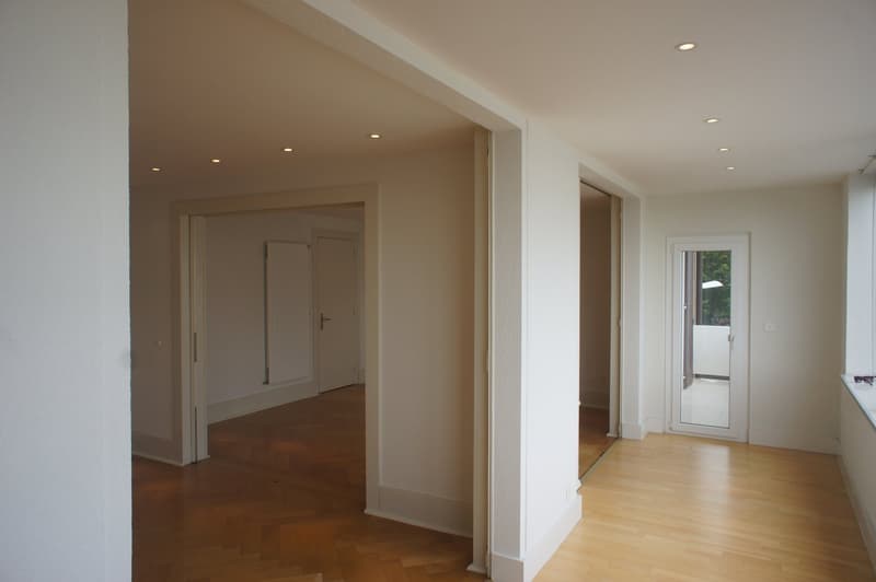 Empty room with wooden floor, white walls, white doors, balcony