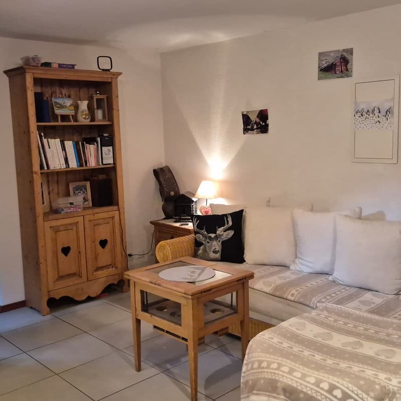 white tiles, a wooden bookshelf, coffee table, couch, lamp, pictures on the wall