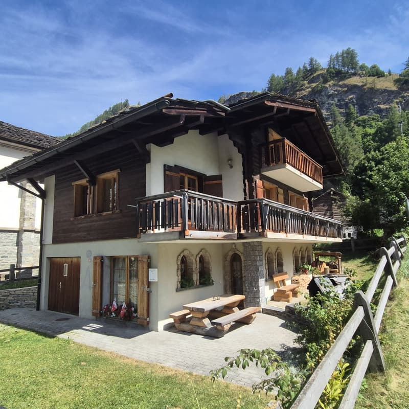 2-story wooden house, wooden balconies, white walls, wooden double doors, wooden picnic table, outdoor seating, wooden fence, grassy yard, mountainous landscape