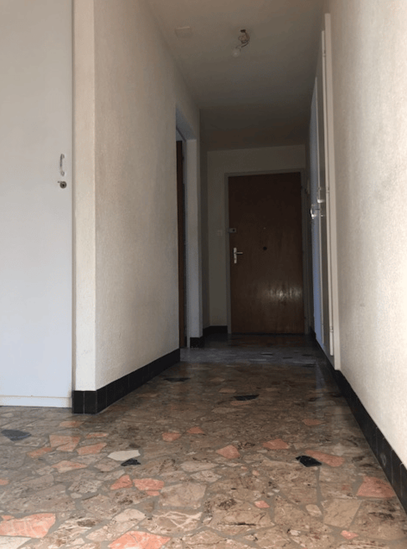 Empty corridor with two doors, tiled floor, light fixtures