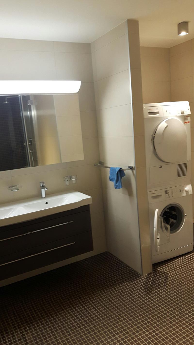 modern bathroom with white tiles, double sink, mirror, washing machine, and dishwasher