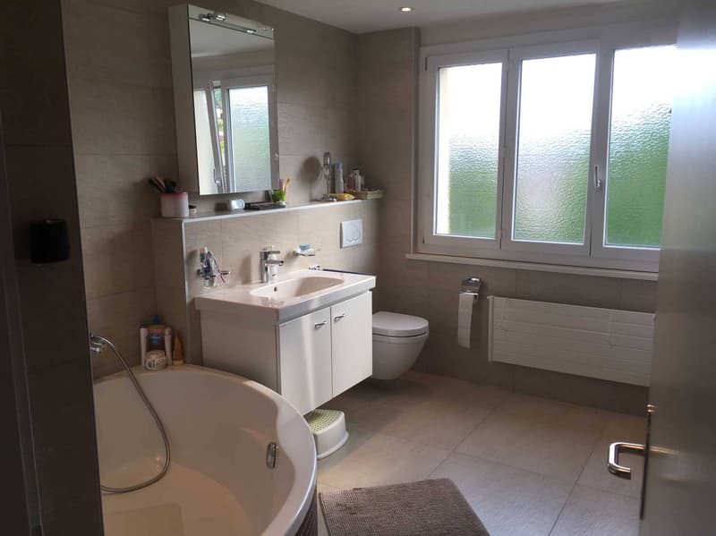 Bathroom with bathtub, sink, toilet, mirror, and windows