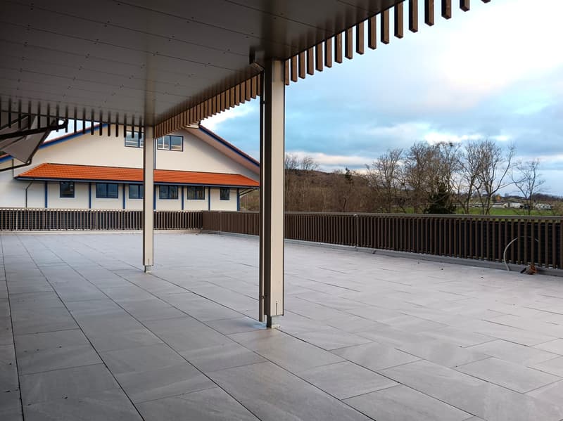 terrace with tiled floor, brown fences, red roof, white house, trees in the background