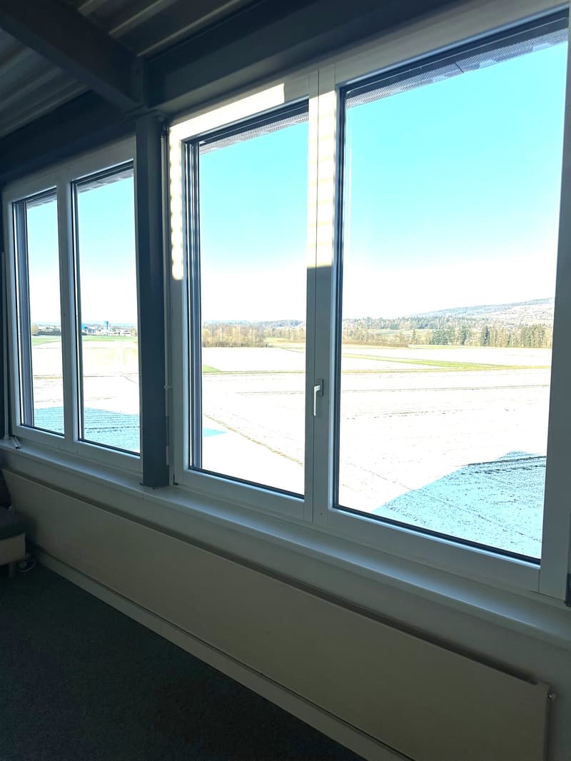 Large window, white wall, radiator, carpet floor, runway view