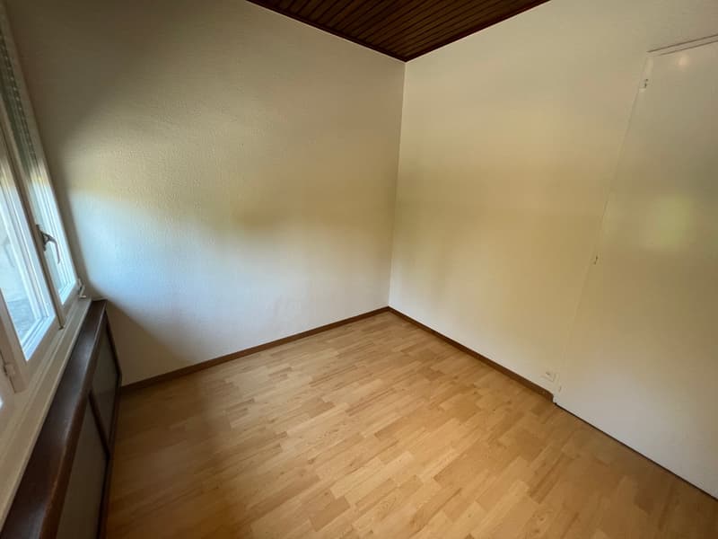 empty room with wooden floors, white walls, window, and wall-mounted radiator