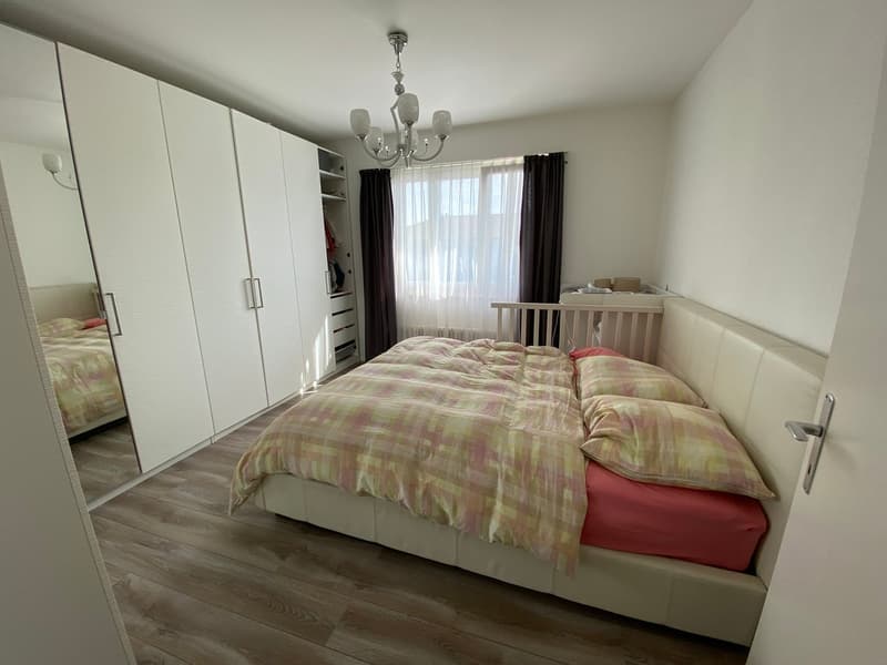large bed, white headboard, white bedspread, white wardrobe, large mirror, chandelier, wooden floor