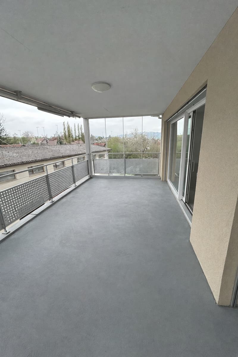Balcony with metal railings, glass doors, and a ceiling light