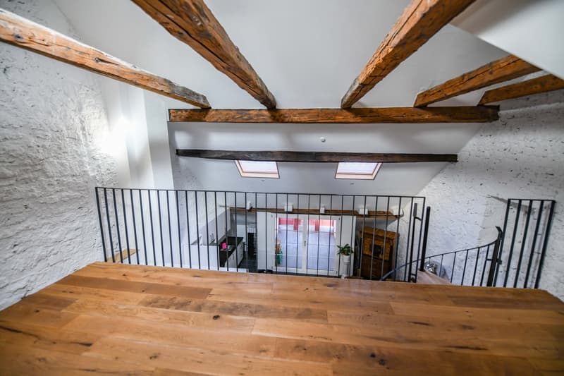 balcony with black railing, wooden beams, white walls, wooden floors, two windows