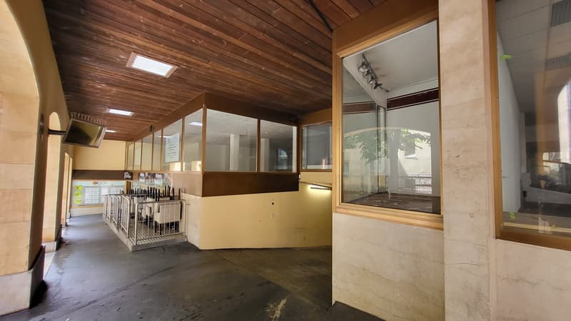 concrete walls, wooden ceiling, tiled floor, large windows, metal railings, glass partition, signage, monitors