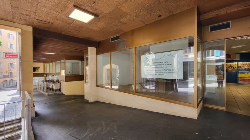 Commercial building entrance with glass walls, wooden ceiling, and illuminated sign