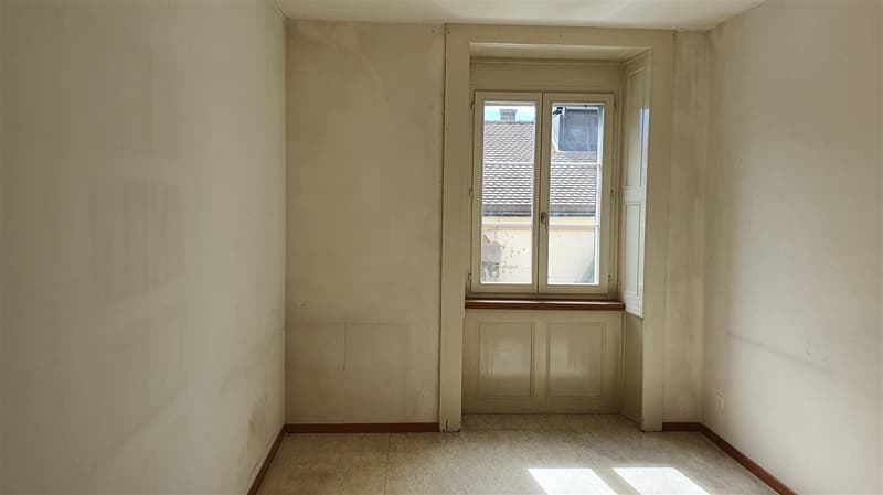 Empty room, white walls, wooden floor, windows with shutters, small window seat