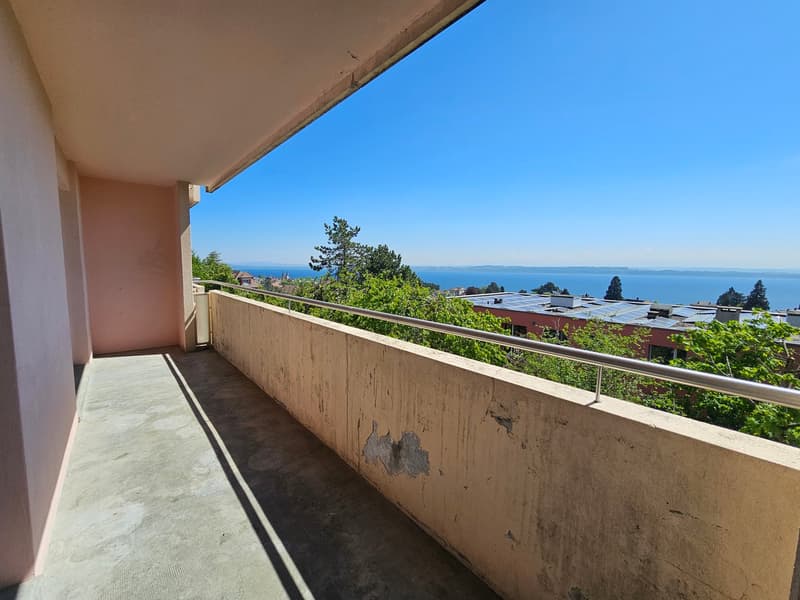 Balcony with railings, concrete floor, view of the sea and trees