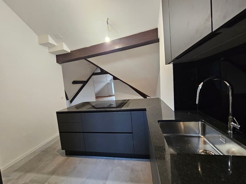 black marble countertop, black cabinets, induction cooktop, stainless steel sink with modern faucet
