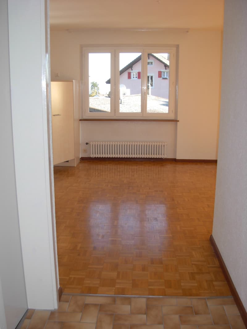 empty room, wooden parquet floor, white walls, large window, white radiator