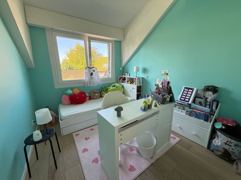 A child's room with a desk, a bed, a rug, and various toys and decorations.