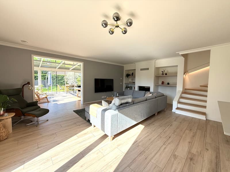 open plan living room, gray sofa, wooden floor, chandelier, TV, glass door, garden view