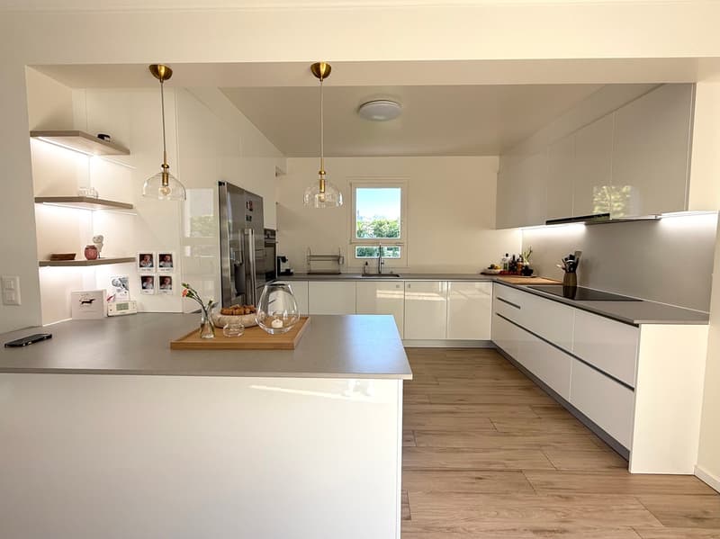 modern kitchen with white cabinets, gray countertops, wooden floors, pendant lights, stainless steel appliances, and a window