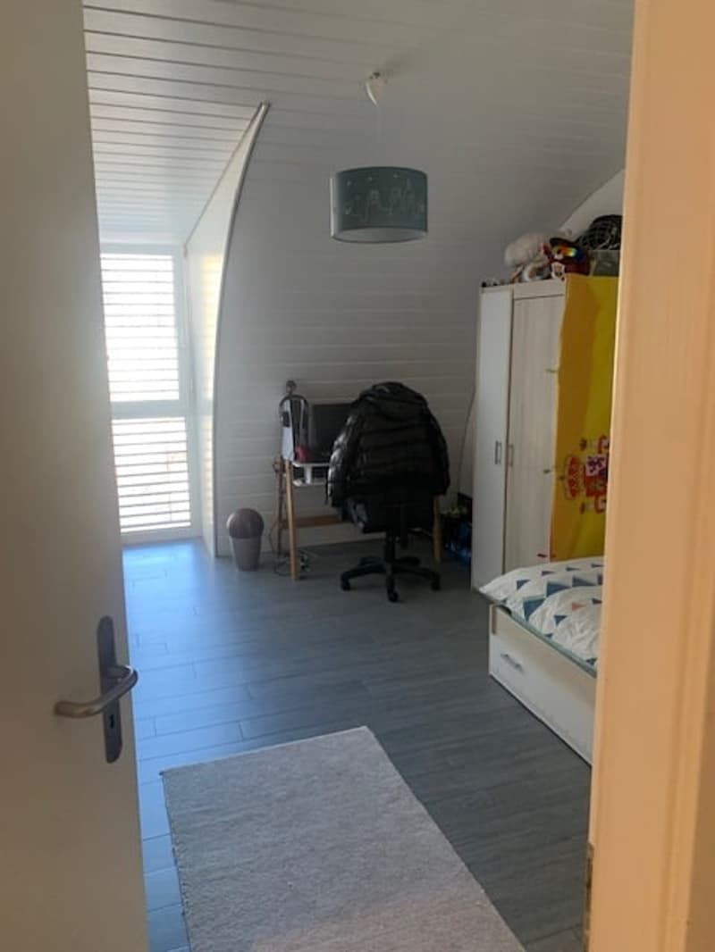 Bedroom with bed, desk, office chair, wardrobe, rug, trash bin, hanging lamp