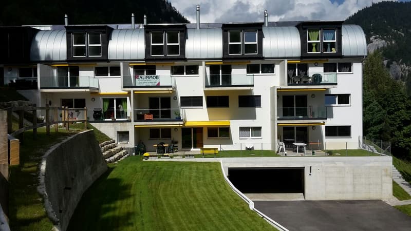 Modern apartment building, multiple floors, white and yellow exterior, balcony on each floor, underground parking area