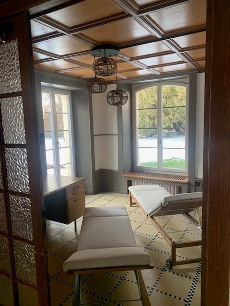 Interior room with tiled floor, wooden ceiling, desk, bench, and large windows