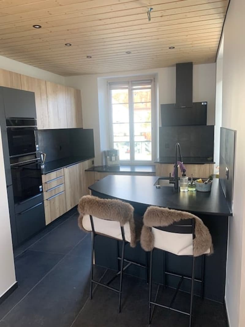 modern kitchen, black countertop, black oven, black sink, stainless steel faucet, wooden cabinets, wooden ceiling