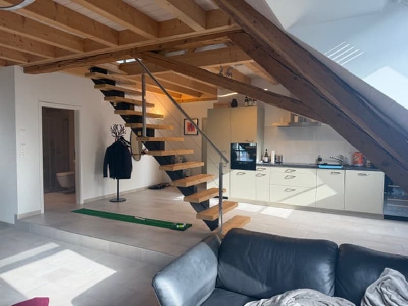 loft-style interior with wooden beams, couch, kitchen area with modern appliances, stairs