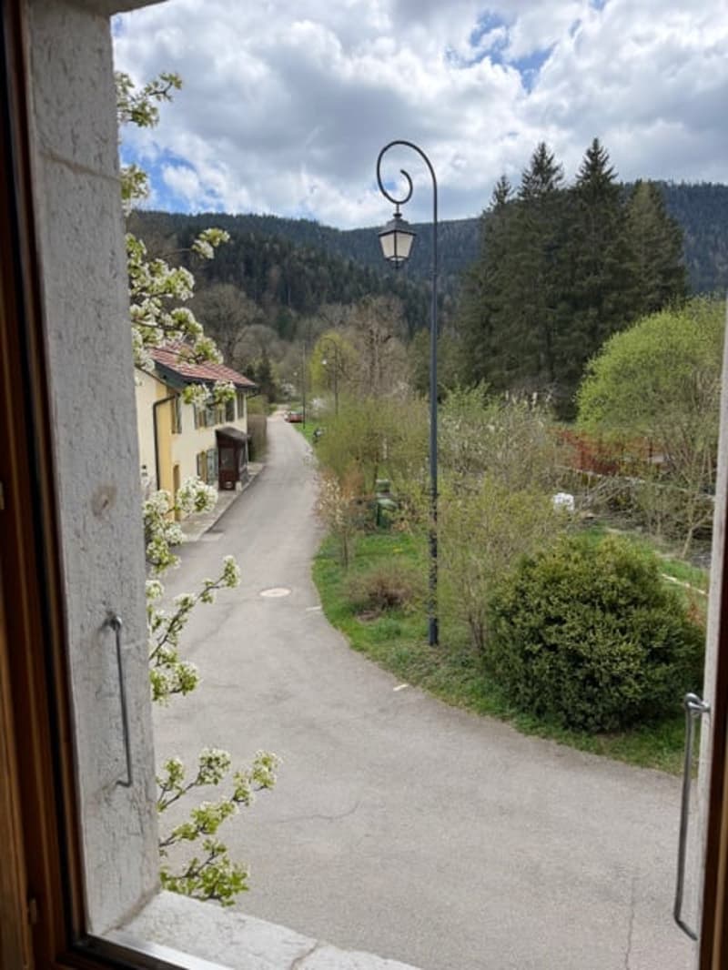 View from a window of a road with a house, street lamp, and mountains in the background