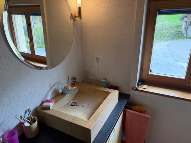 Bathroom with a large sink, mirror, and a window with a view of the outside