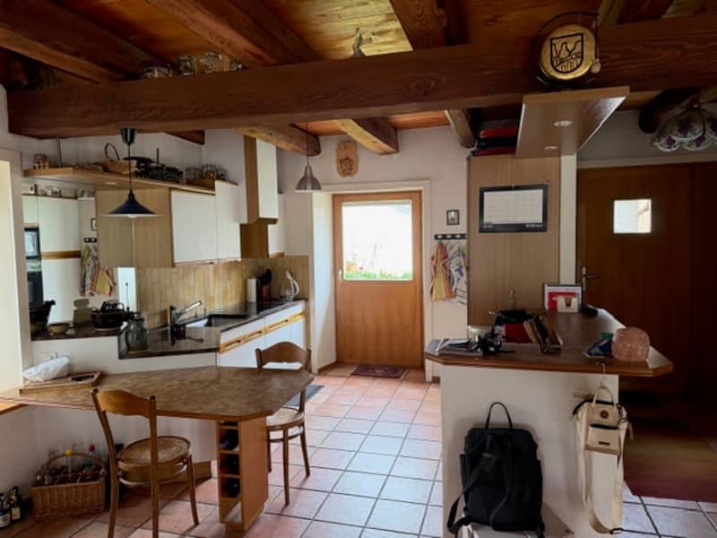 kitchen with dining area, wooden table, chairs, wooden beams, tiled floor, wooden door, kitchen appliances, shelves, baskets, bags