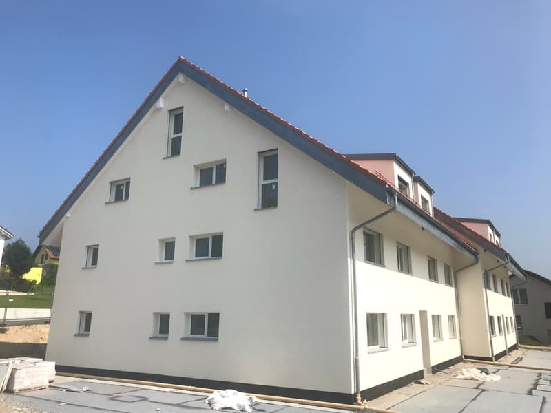 3-story residential building with white exterior walls, red tile roof, and multiple windows. The building appears to be newly constructed or recently renovated.