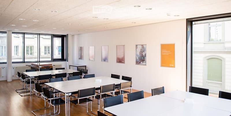 empty conference room with rows of tables and chairs, large windows